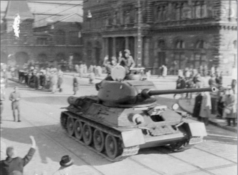Original caption Hungarian Army crewmen wave to passersby from the turret of their tank in a Budapest street.
